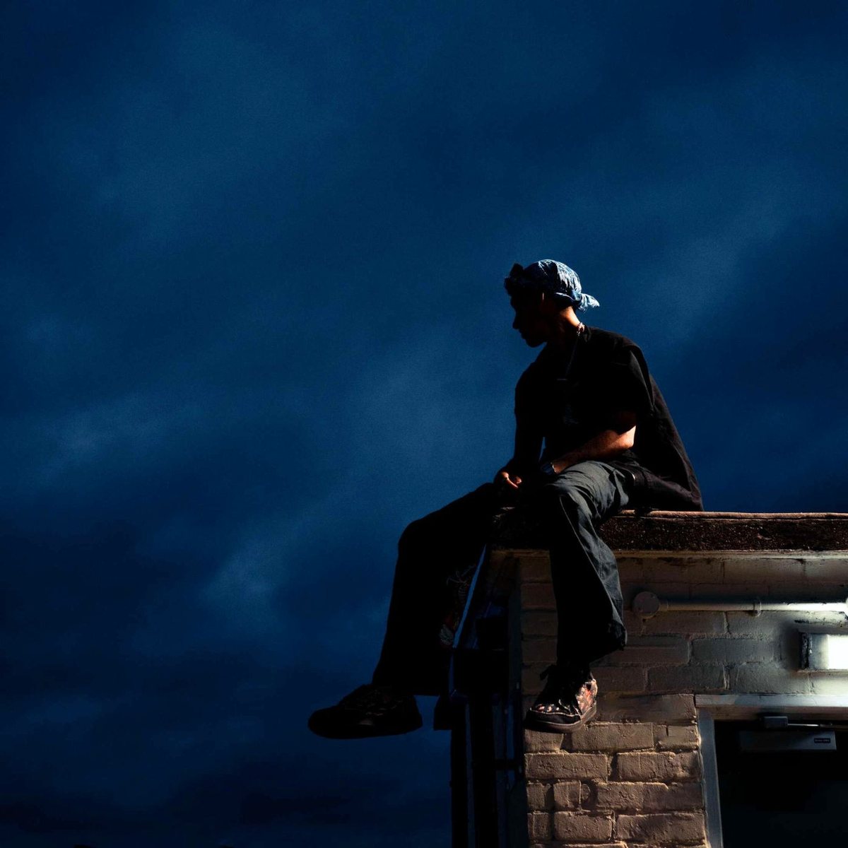 Life Is But a Dream cover art: a lone figure sitting on a rooftop ledge against a deep midnight blue sky