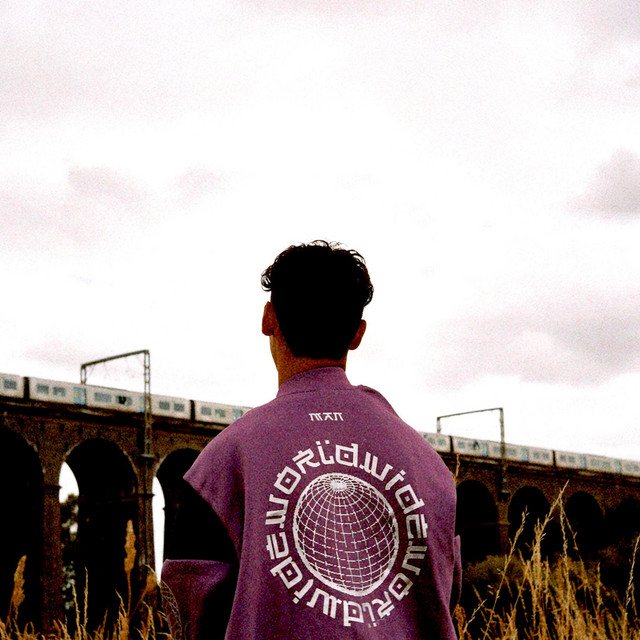 Lost City cover art: Stephen Mathes photographed from behind in a purple Worldwide fleece, facing a brick railway viaduct under a pale sky