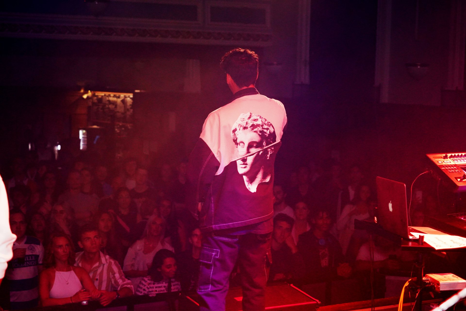 The view from the stage: Stephen Mathes facing a packed crowd under pink and red light