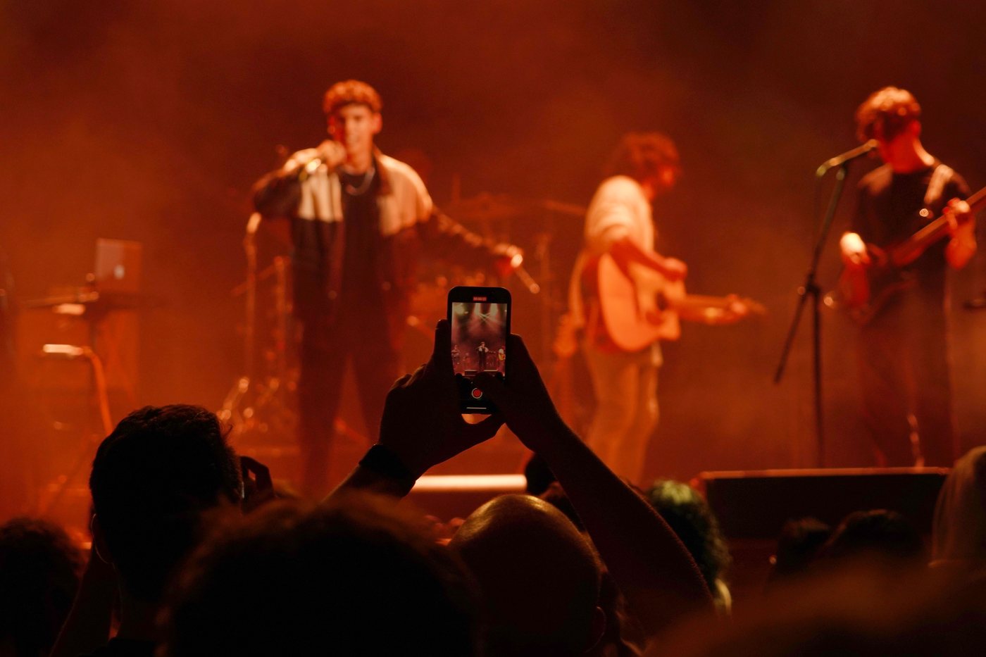 A crowd lit in amber with a phone raised to film the stage