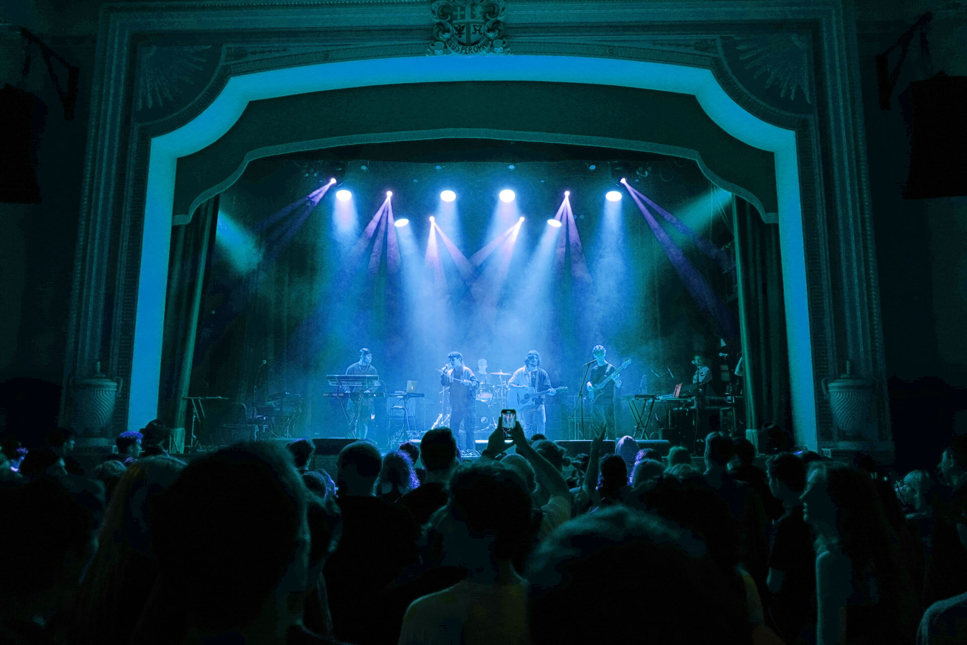 Stephen Mathes and his band on stage at Islington Assembly Hall in blue light above a full crowd