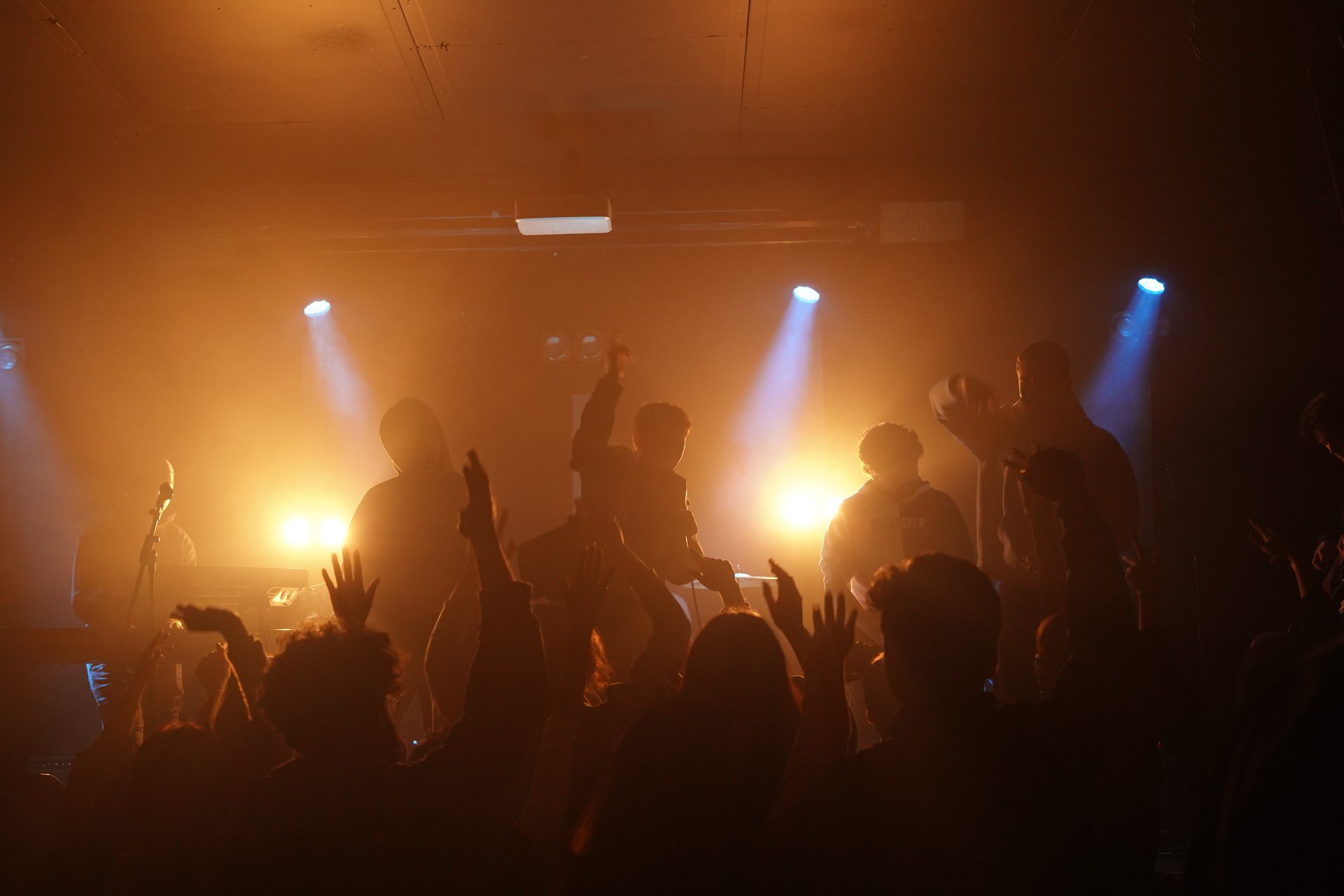 Stephen Mathes in silhouette against amber haze and a bank of stage lights