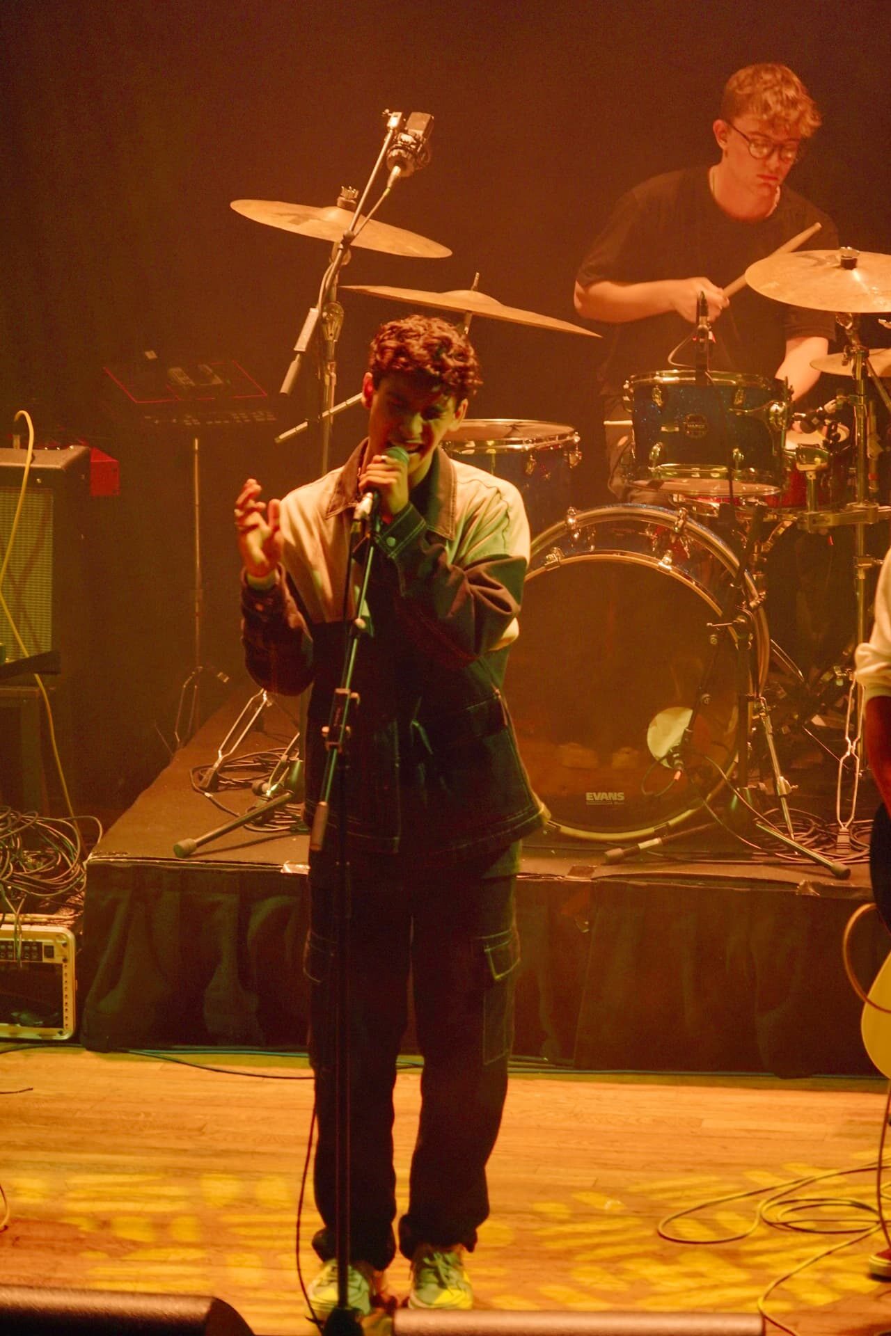 Stephen Mathes singing into a microphone on a stand with the drummer behind him